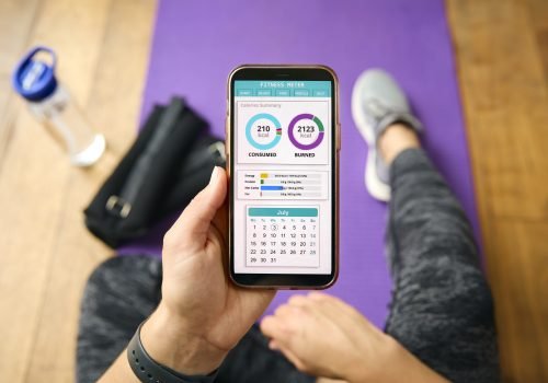 Close Up Of Woman With Smart Watch About To Exercise Looking At Fitness App On Mobile Phone