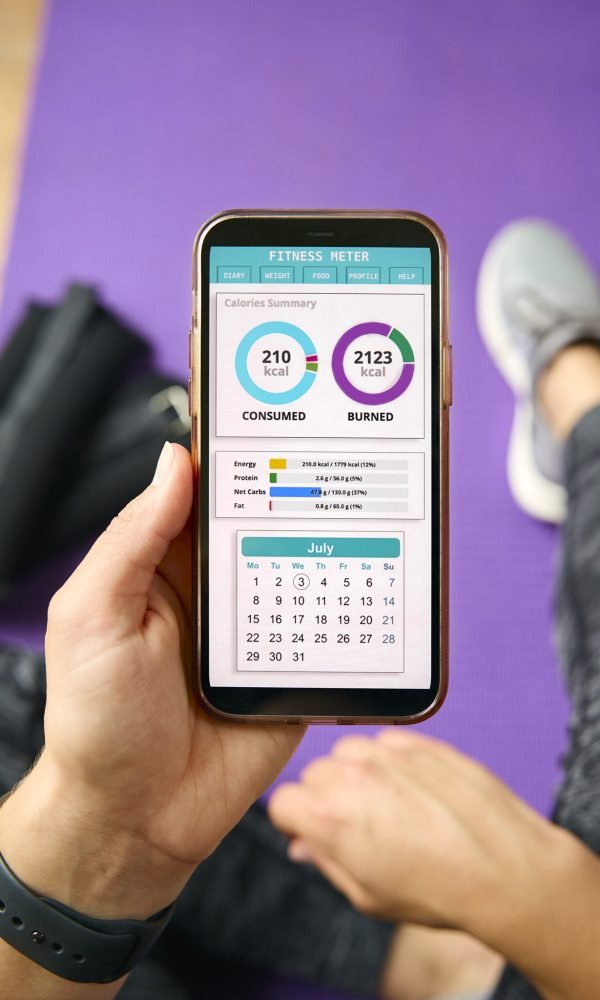 Close Up Of Woman With Smart Watch About To Exercise Looking At Fitness App On Mobile Phone