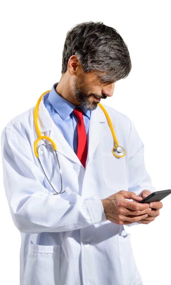 Male doctor in his 50s wearing a white lab coat and stethoscope standing watching media on his smartphone with a quiet smile isolated on white