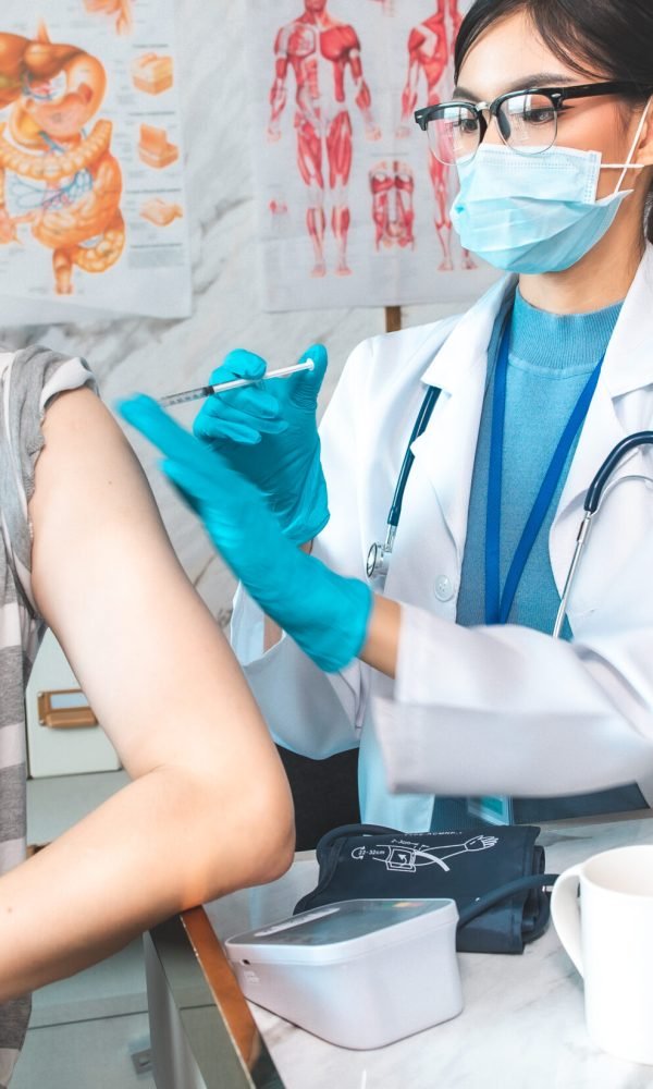 Vaccination, immunization, disease prevention concept. people in medical face mask getting Covid-19 or flu vaccine at the hospital. Professional nurse or doctor giving antiviral injection to patient.