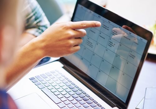 Close-up image of production team discussing working calendar for a month on laptop screen
