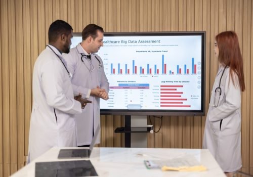Team of doctors discuss healthcare big data to analyze patient satisfaction trends, waiting status, turnover rates aiming to identify areas for improvement, create cost effective management plans.